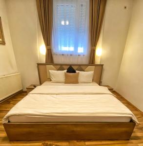 Schlafzimmer mit einem großen Bett und einem Fenster in der Unterkunft Golden BnB Hotel in Pristina