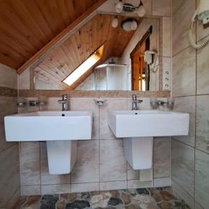 two sinks in a bathroom with a wooden ceiling at Зарінок карпат in Mykulychyn +63 photos