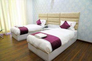 two beds in a room with purple and white at Lime Tree Hotel Pulkit Gurgaon-Artemis Hospital, Nearest Metro Huda City Centre in Gurgaon