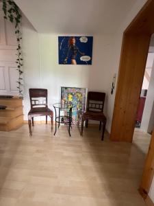 Zimmer mit 2 Stühlen, einem Tisch und einem Gemälde in der Unterkunft Historische Villa Velden im Zentrum in Velden am Wörthersee