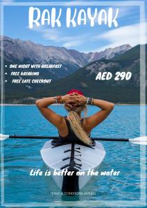 a woman is sitting on a paddle board in the water at Mangrove Hotel in Ras al Khaimah