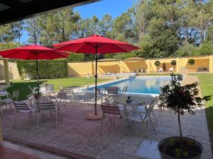a group of tables and chairs with umbrellas next to a pool at Quinta Dos Amarelos no Meco in Aldeia do Meco