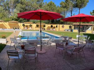 a group of tables and chairs with umbrellas next to a pool at Quinta Dos Amarelos no Meco in Aldeia do Meco