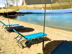 two beach chairs under an umbrella on the beach at Casa Santa Agua in Ammouliani