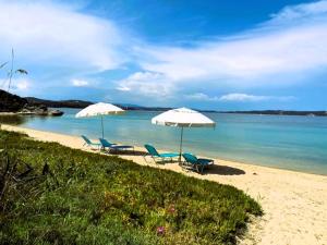 2 Stühle und Sonnenschirme am Strand mit Meerblick in der Unterkunft Casa Santa Agua in Amolianí