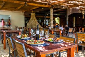 a wooden table with two plates of food and wine glasses at Lavanda Luxury Mobile Home at Terra Park Spiritos camp in Kolan
