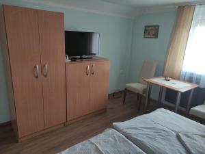 a bedroom with a bed and a television on a cabinet at Molnár Vendégház in Bük