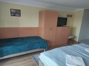 a bedroom with a bed and a cabinet and a television at Molnár Vendégház in Bük