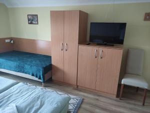 a bedroom with a bed and a television and a chair at Molnár Vendégház in Bük