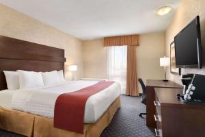 a hotel room with a bed and a desk and a television at Travelodge by Wyndham North Battleford in North Battleford +6 photos