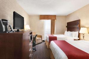 a hotel room with two beds and a flat screen tv at Travelodge by Wyndham North Battleford in North Battleford