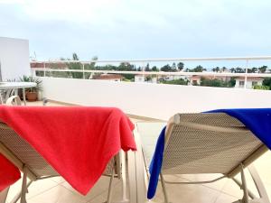 uma toalha vermelha e azul sentada em duas cadeiras numa varanda em Nissi 3 C14 Sea View Top Floor Apartment em Agia Napa