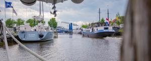 een groep boten is aangemeerd in een jachthaven bij Unieke woonboot in Harlingen in Harlingen