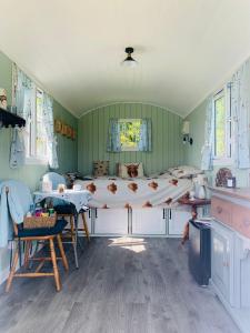 1 dormitorio con 1 cama grande, mesa y sillas en Bells Meadow Shepherds Hut en Kings Lynn