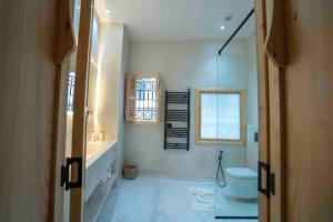 uma casa de banho com uma banheira, um WC e uma janela. em Riad Zhor Tanger - Médina em Tânger
