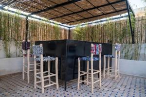 un bar avec trois tabourets devant une table dans l'établissement Riad Zhor Tanger - Médina, à Tanger