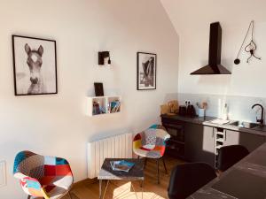 - une cuisine avec un bureau et des chaises dans la chambre dans l'établissement Gîtes L'Ancienne Ecurie - L'Ancien Atelier, à Saint-Quentin-en-Tourmont