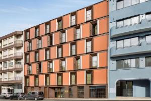 an orange building with cars parked in front of it at Fontinha Porto, Trademark Collection by Wyndham in Porto