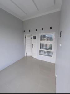 une chambre vide avec des murs blancs et une fenêtre dans l'établissement Family Homestay Bukit Ambacang, à Gadut