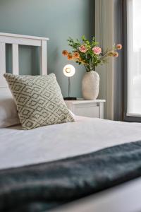 Cama con almohada y jarrón con flores en Charming getaway in the historical city center en Brujas