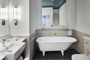 a white bathroom with a tub and a sink at Bournemouth Highcliff Marriott Hotel in Bournemouth