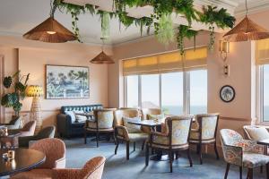 a restaurant with tables and chairs and windows at Bournemouth Highcliff Marriott Hotel in Bournemouth