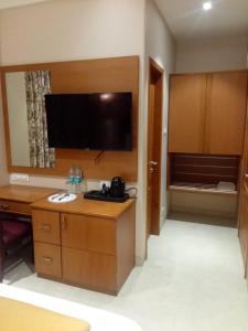 MUZA HOTELS FISCO في مومباي: غرفة في الفندق مع مكتب وتلفزيون بشاشة مسطحة