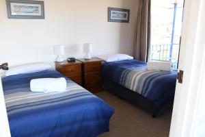 a hotel room with two beds and a laptop on it at Narooma Palms Holiday Apartments in Narooma