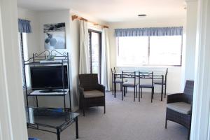 ein Wohnzimmer mit einem Tisch, Stühlen und einem TV in der Unterkunft Narooma Palms Holiday Apartments in Narooma