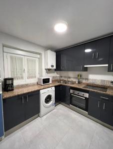 una cocina con armarios negros, lavadora y secadora en Piso Los Jardines, en Peñaranda de Bracamonte