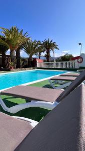 una piscina con varias sillas y palmeras en Salobre Blue Sky 2 - Adults Only, en Salobre