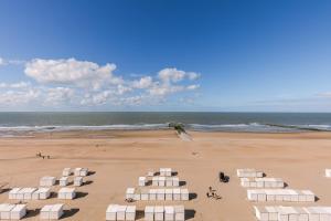 a beach with white lounges and a kite flying over the ocean at Magnificent Apartment with Great Panoramic Seaview in De Haan