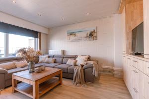 a living room with a couch and a table at Magnificent Apartment with Great Panoramic Seaview in De Haan