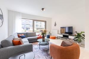 een woonkamer met een bank en een tv bij Brand new holiday home with high-end finishing and private parking space, at a stone's throw from the beach in Oostende