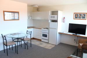 una pequeña cocina con mesa y TV. en Narooma Palms Holiday Apartments en Narooma