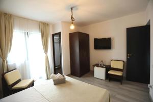 ein Hotelzimmer mit einem Bett, 2 Stühlen und einem TV in der Unterkunft Casa Izabela in Năvodari