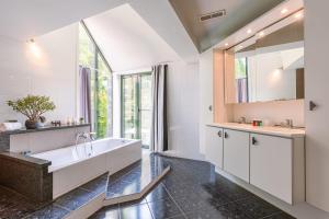 baño con bañera grande y ventana en Peacefully located villa with stunning garden and hot tub, en Oostkamp