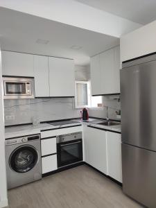 a kitchen with white cabinets and a washer at apartamento vacacional in Calpe