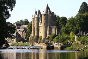 un castillo sentado al lado de un cuerpo de agua en Cosy'Appart hyper centre Josselin, en Josselin