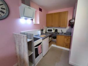 uma pequena cozinha com paredes cor-de-rosa e um relógio na parede em Cosy'Appart hyper centre Josselin em Josselin