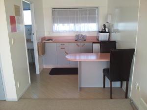 een kleine keuken met een tafel en 2 stoelen bij Norfolk Motel & Campervan Park in Awanui