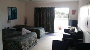 una camera d'albergo con due letti e una porta scorrevole in vetro di Norfolk Motel & Campervan Park ad Awanui