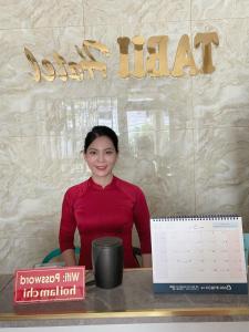 a woman is sitting at a desk with a calendar at Tabii hotel in Da Nang