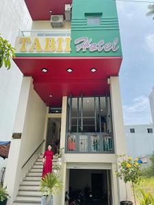 a woman in a red dress standing outside of a restaurant at Tabii hotel in Da Nang