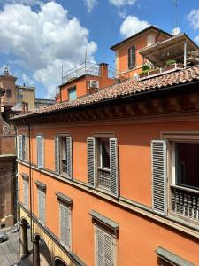 an orange building with white shutters on it at Bibliò Rooms Guesthouse in Bologna