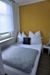 a bed with white pillows in a room with a window at Ferienwohnung TrautesHeim - Parkplatz gratis in Ilmenau