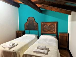 2 Betten in einem Zimmer mit blauer Wand in der Unterkunft L'antico Borgo in Cremia