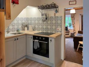 a kitchen with a stove top oven next to a living room at Bluebell Cottage in Garstang