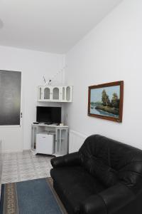 un sofá de cuero negro en una sala de estar con TV en Villa Deart Berat, en Berat