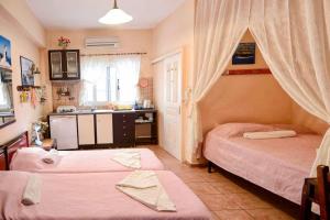 a bedroom with two beds and a kitchen with a sink at Ikaria Studios in Manganítis